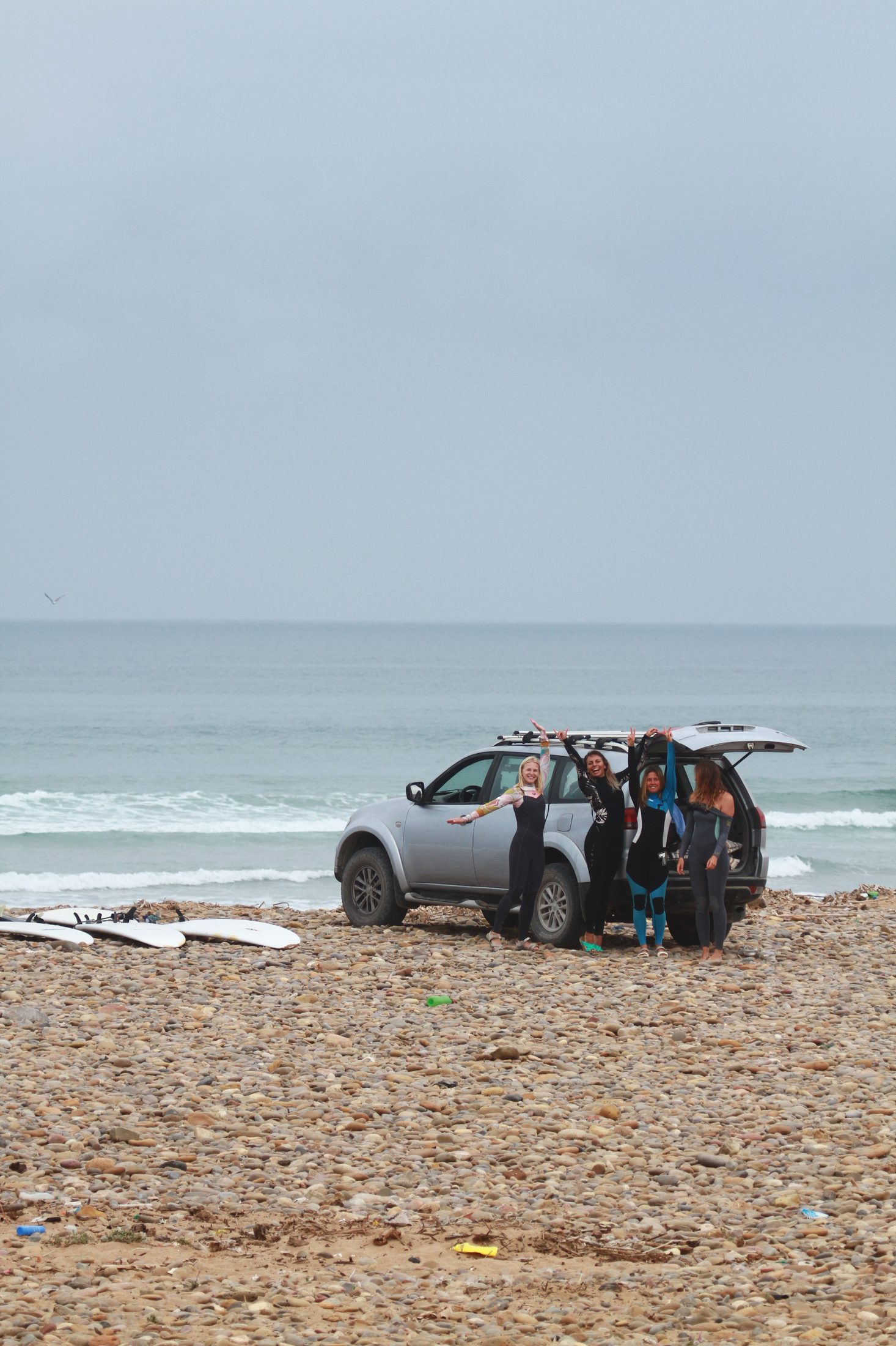 Group of surfers with boards and the camp van on the beach